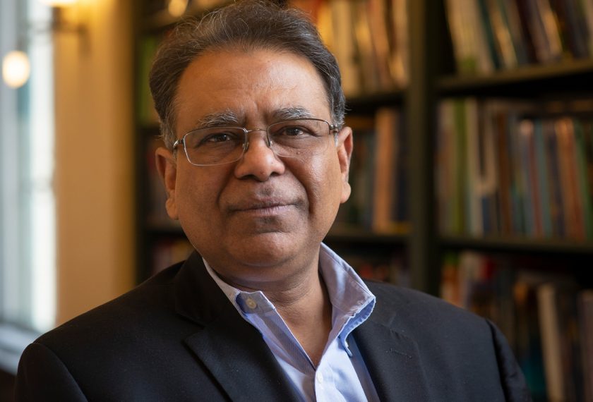 Arup Chakraborty smiles in front of packed bookshelves.