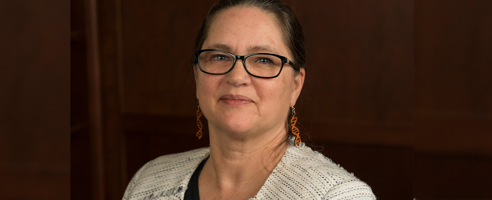 Catherine Drennan smiles in front of a wood paneled wall.