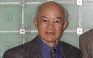 T. Y. Shen smiles in front of a periodic table.