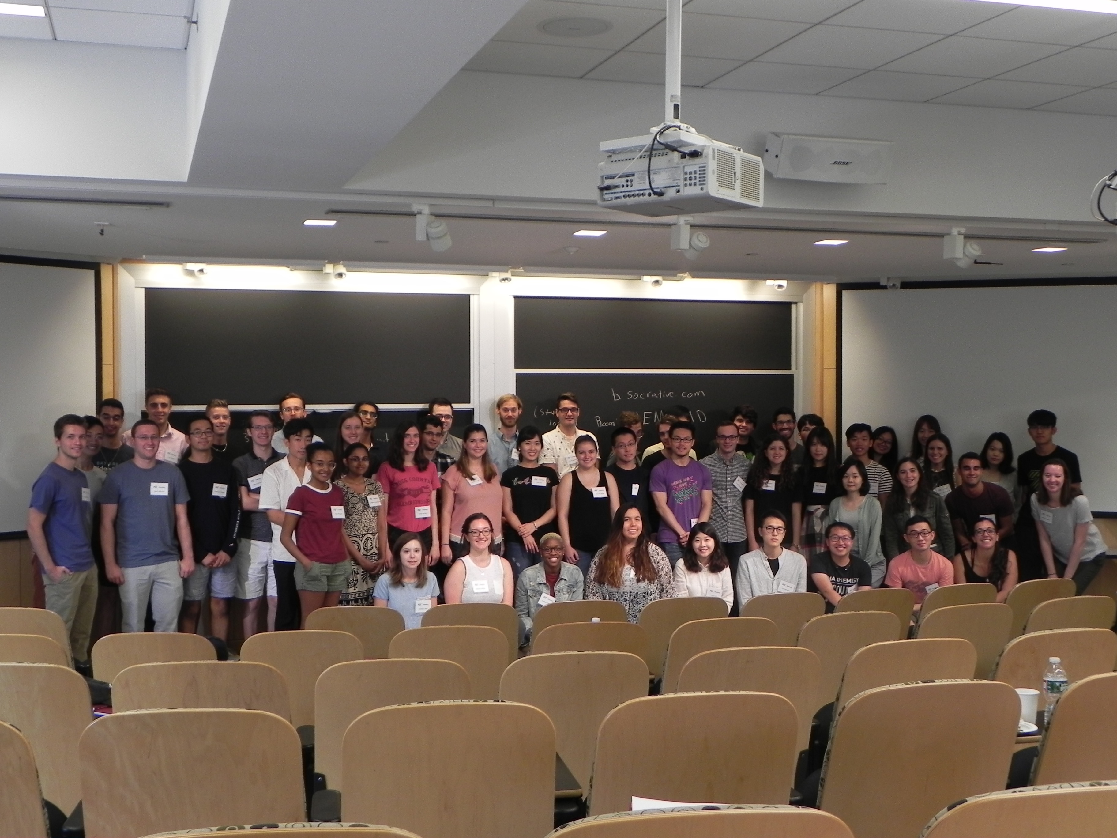 Group photo of first year graduate students standing in a lecture hall