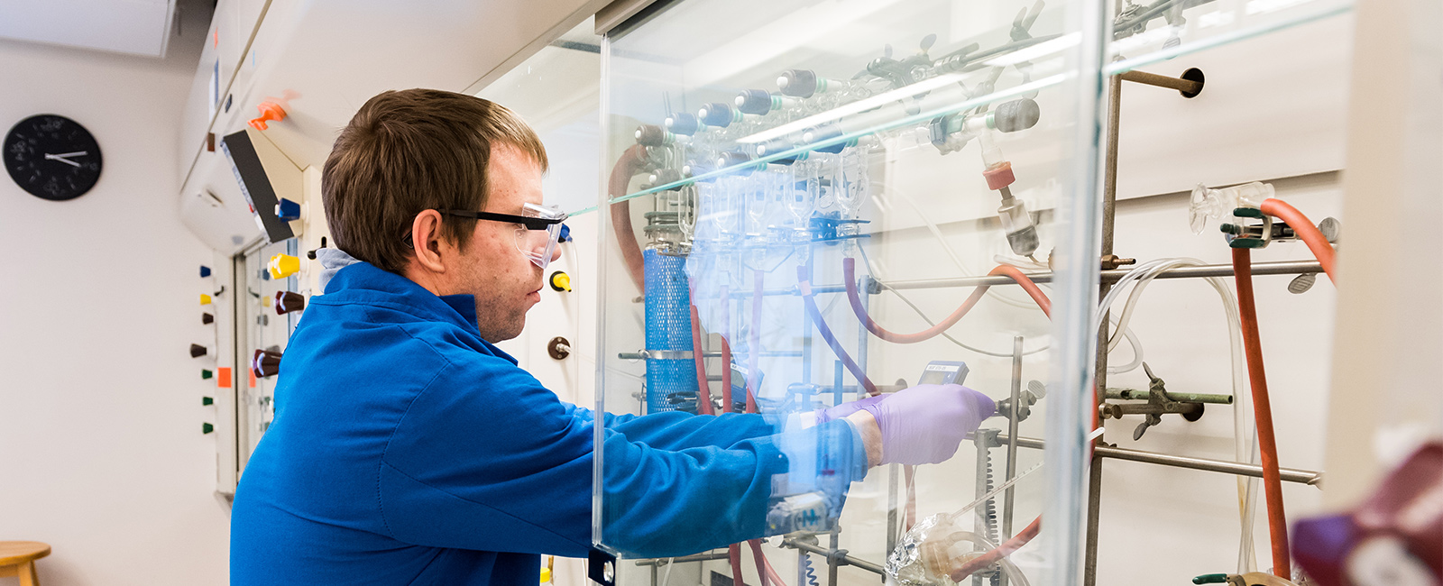 A graduate student conducts research at a fume hood.