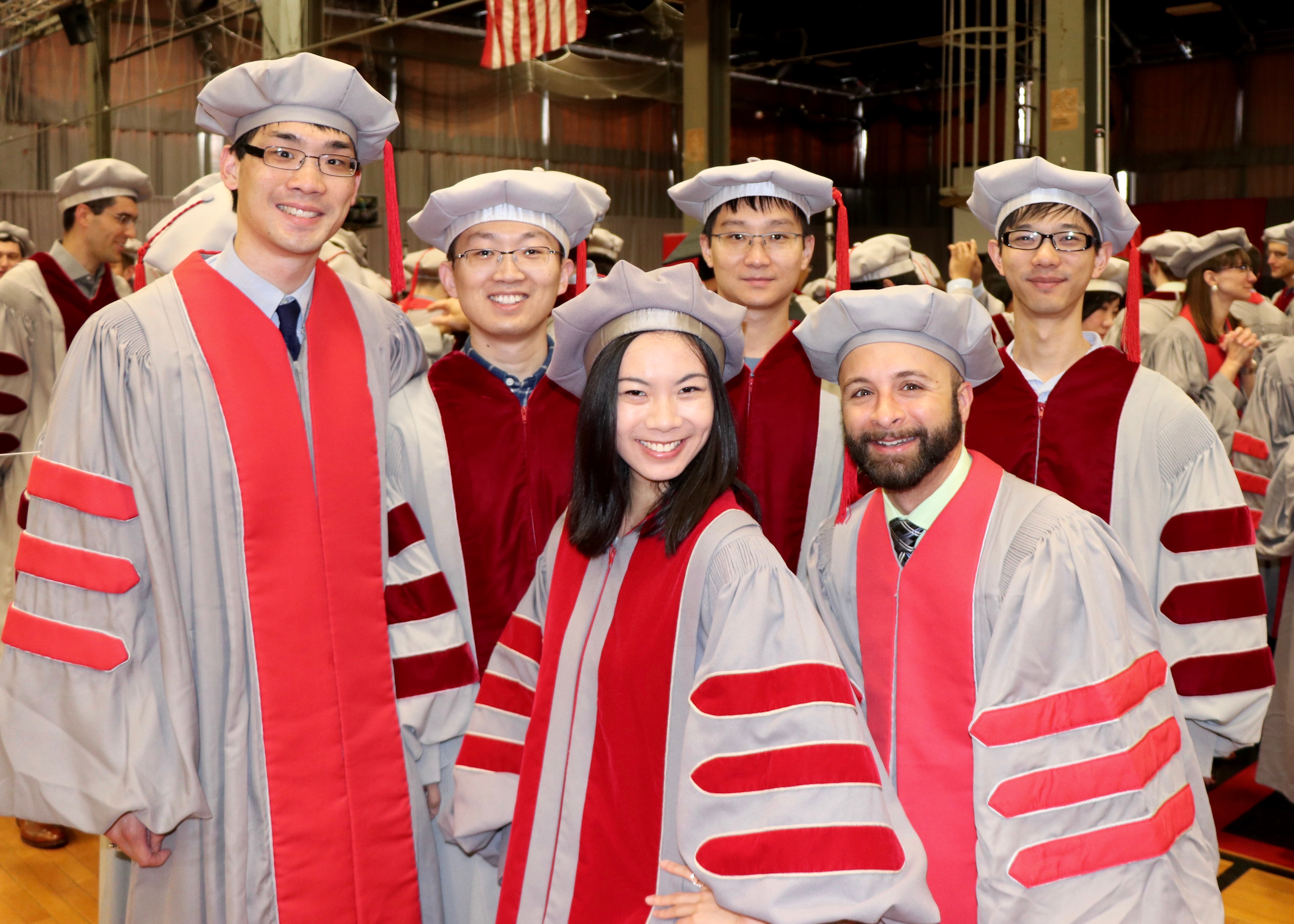 PhD recipients smile together before receiving their doctoral hoods