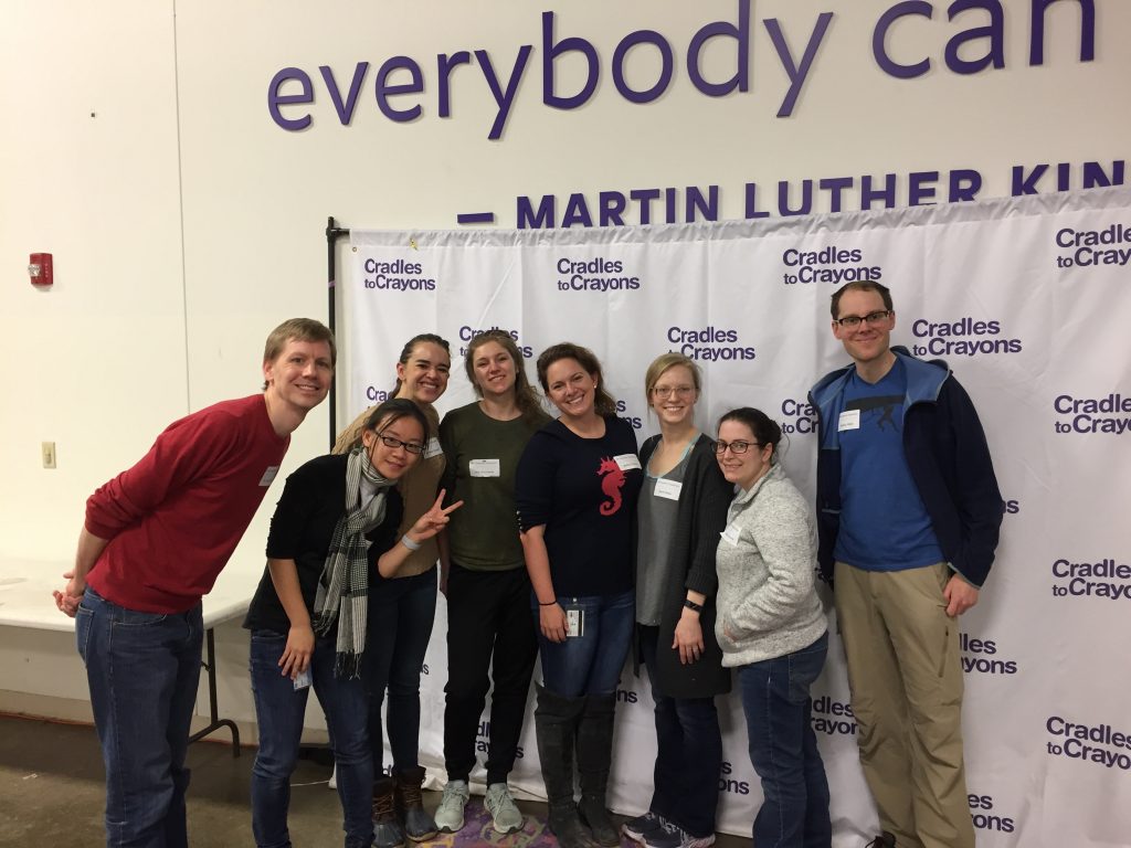 A group smiles while volunteering at a warehouse.