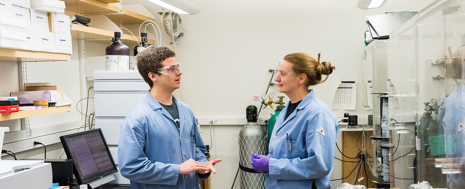Two graduate students talk about their research in a lab.
