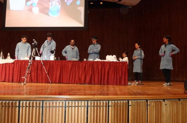 Members of Club Chem present a Chemistry Magic Show on stage before an audience.