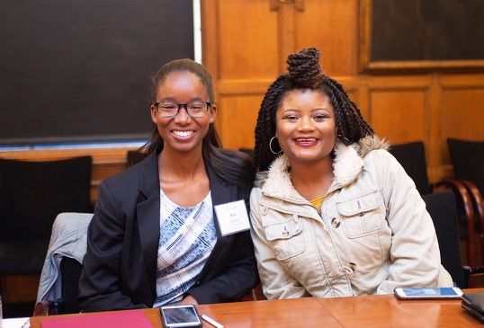Two female ACCESS participants smile together sitting at a table.