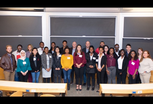 Two male professors pose with a group of 23 student program participants.