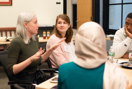 A female current MIT graduate students engages with two female program participants at lunch.
