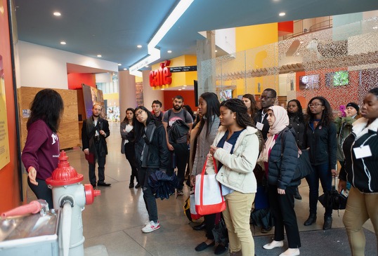 A group of students listens to an anecdote while taking a tour of a student center.
