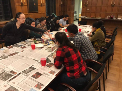 A group of CADI members gather around a newspaper covered table, where they are painting and doing other arts and crafts.