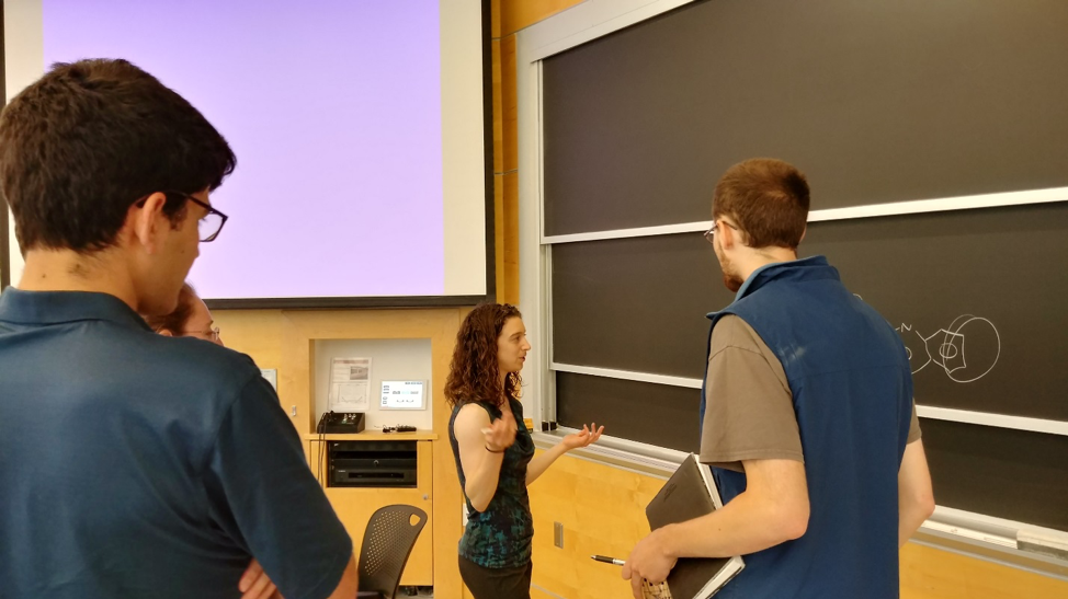 A female student presents a seminar before an audience of fellow students and postdocs.
