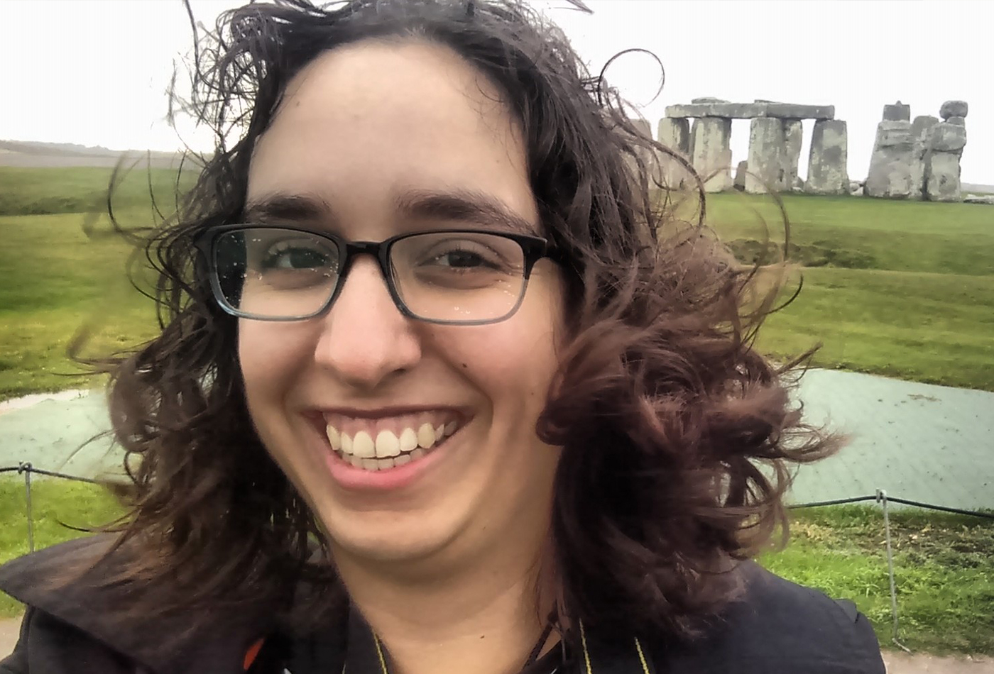 A female graduate student takes a self portrait in front of Stonehenge.