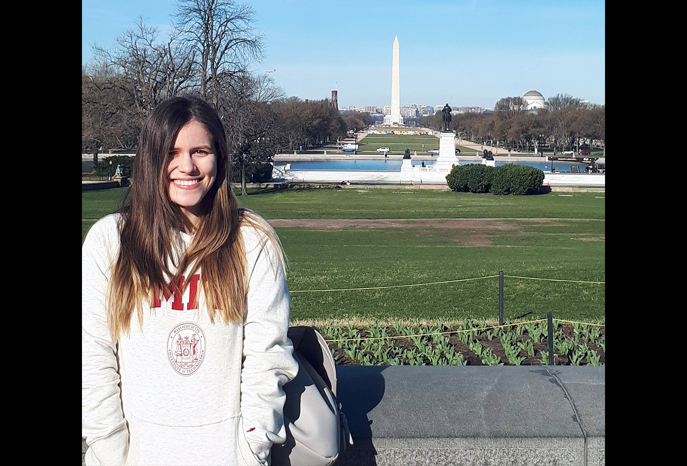 A female graduate student stands in front of the Washington Monument
