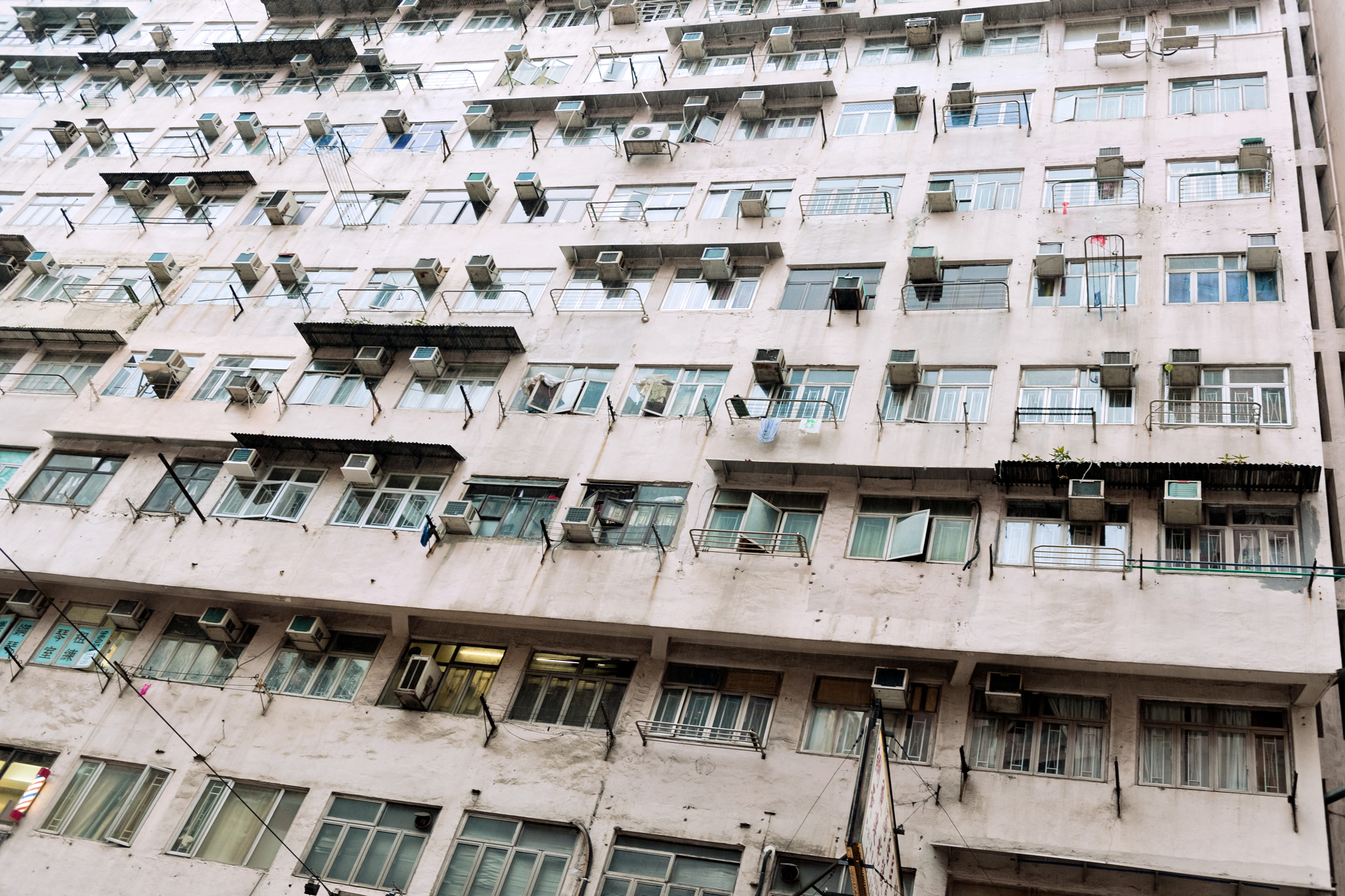 An apartment building littered with air conditioning units on every window.