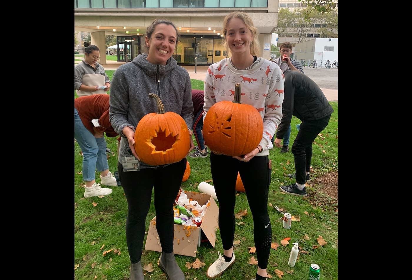 Two graduate students pose with their carved pumpkin