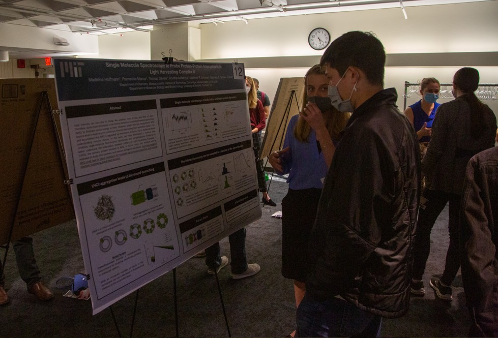 Two people on the right look at a poster on stand to the left