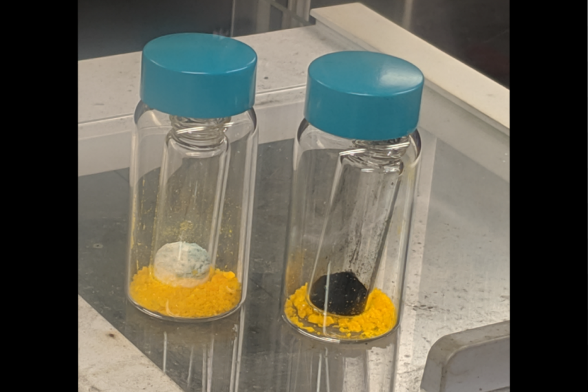 Two vials, both containing a yellow substance with an additional white substance in the one on the left and black substance in the one on the right.right.