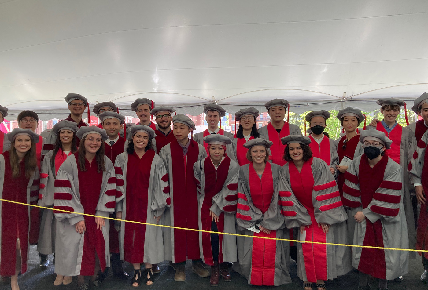 A group of graduates gather in their grey and maroon graduation regalia.