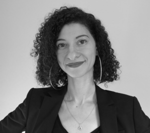 A woman smiles against a plain background in a black and white headshot.