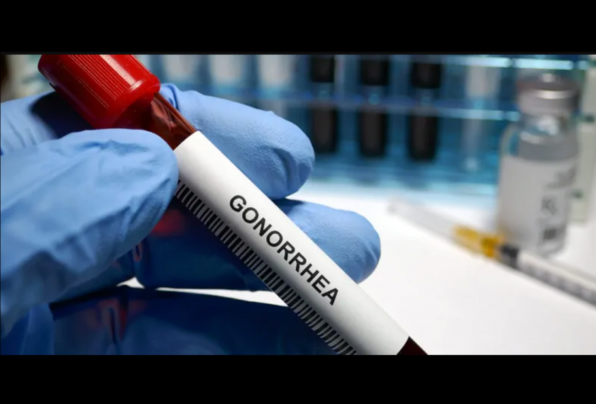 A gloved hand holds a vial of blood labeled gonorrhea.