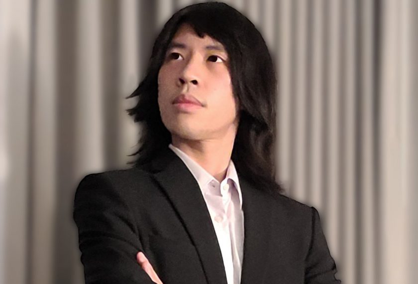 Andrew Lew is photographed in a black suit in front of a white curtain.