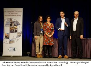 Two women and two men stand in a row on a stage accepting an award .