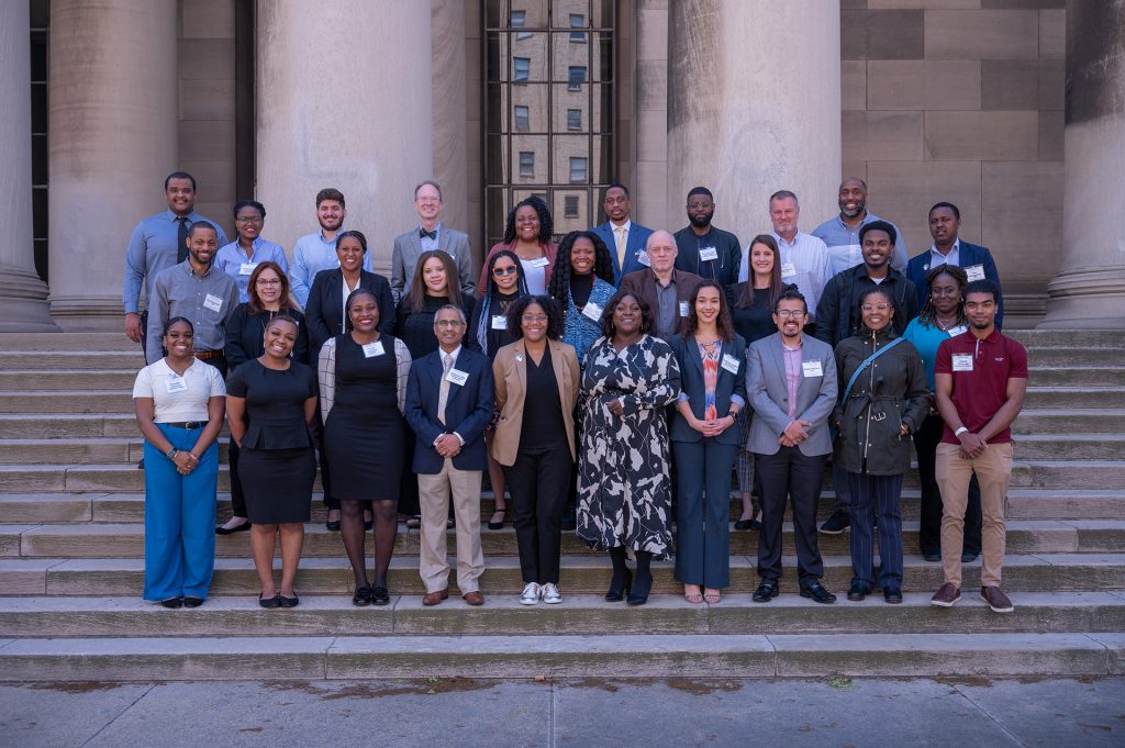 Three rows of Charter 2 Collaborative members smile on the steps of a stately building.