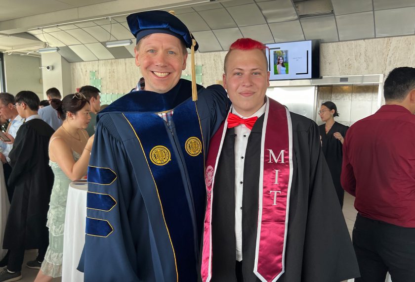 Professor Troy Van Voorhis and Anton Morgunov stand side by side in commencement robes.