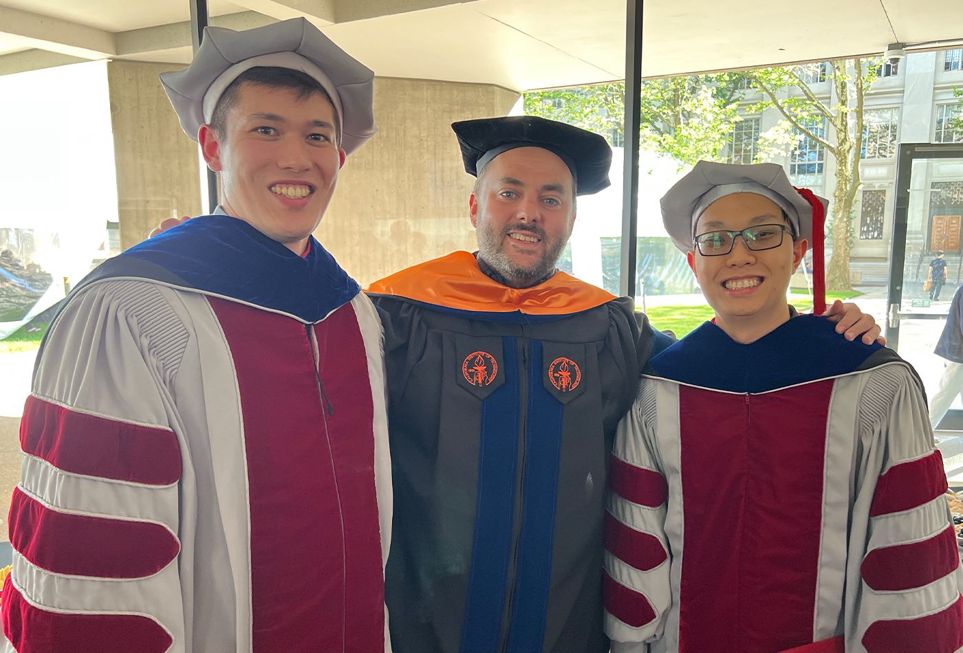 Professor Dan Suess stands with two newly minted PhD recipients.