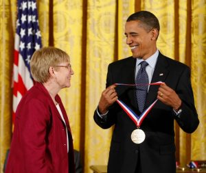 Professor JoAnne Stubbe receives a gold medal on a red and white and blue ribbon from President Obama.