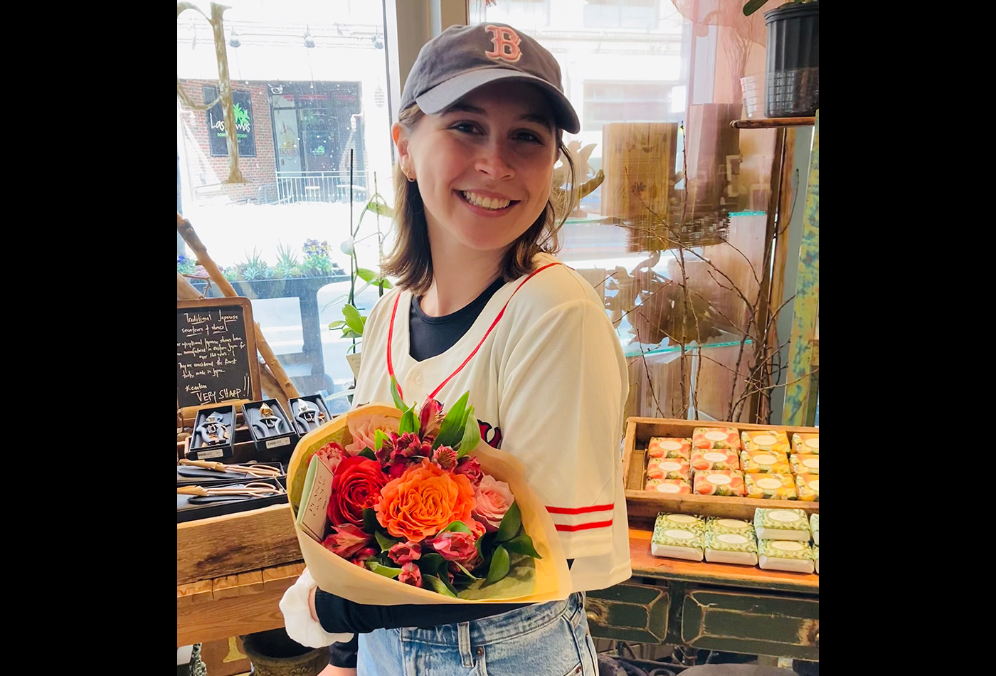 Anna Davis smiles while wearing a Red Sox cap and holding a bouquet of flowers