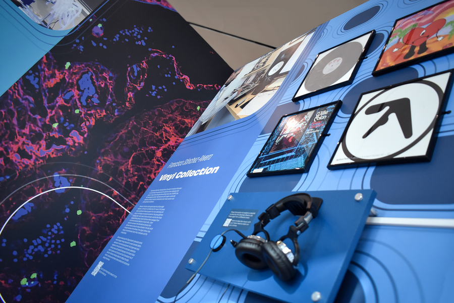 A view of an exhibit panel with a display of record sleeve and a listening station with headphones.