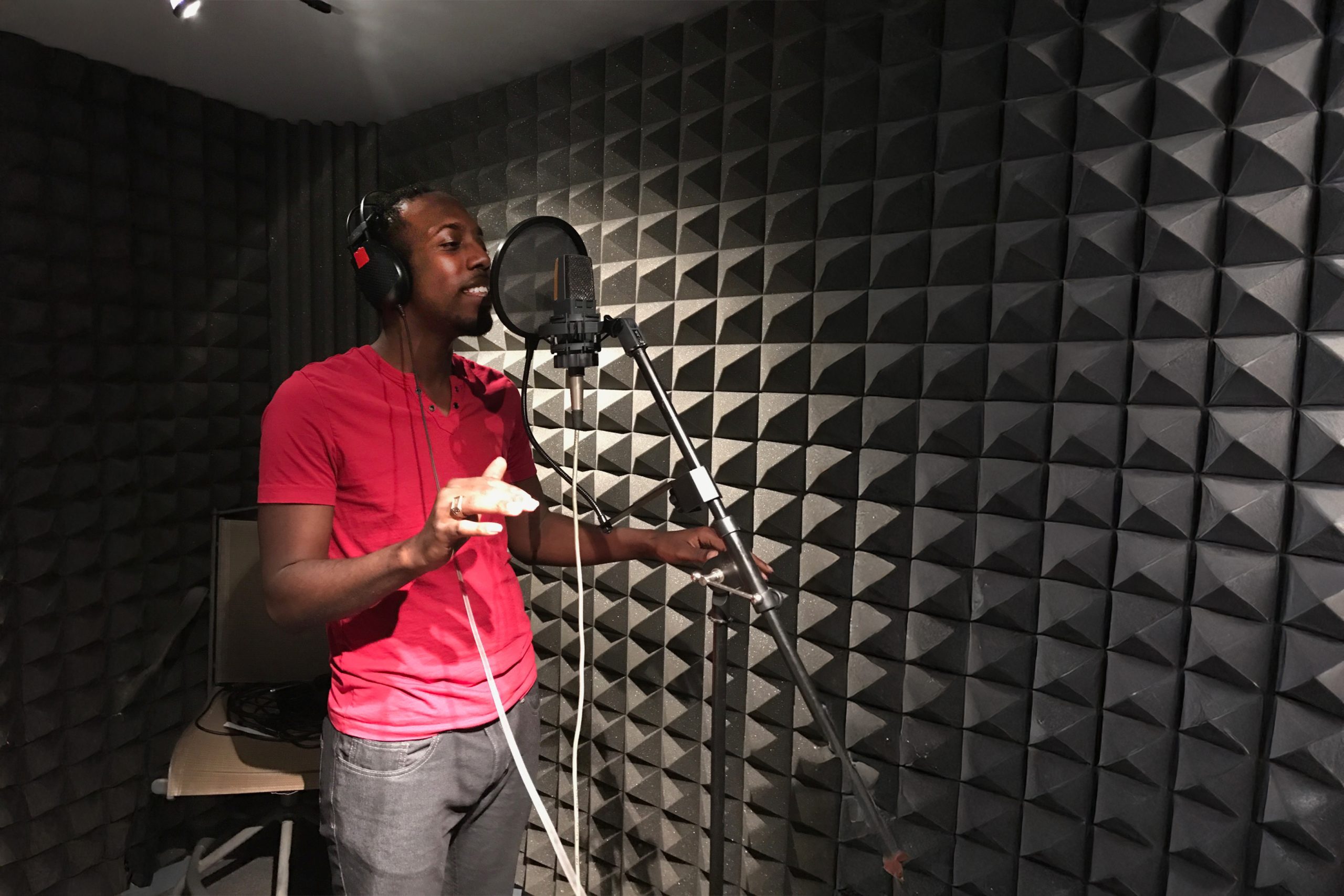 Kelvin Frazier sings into a microphone in a recording studio.