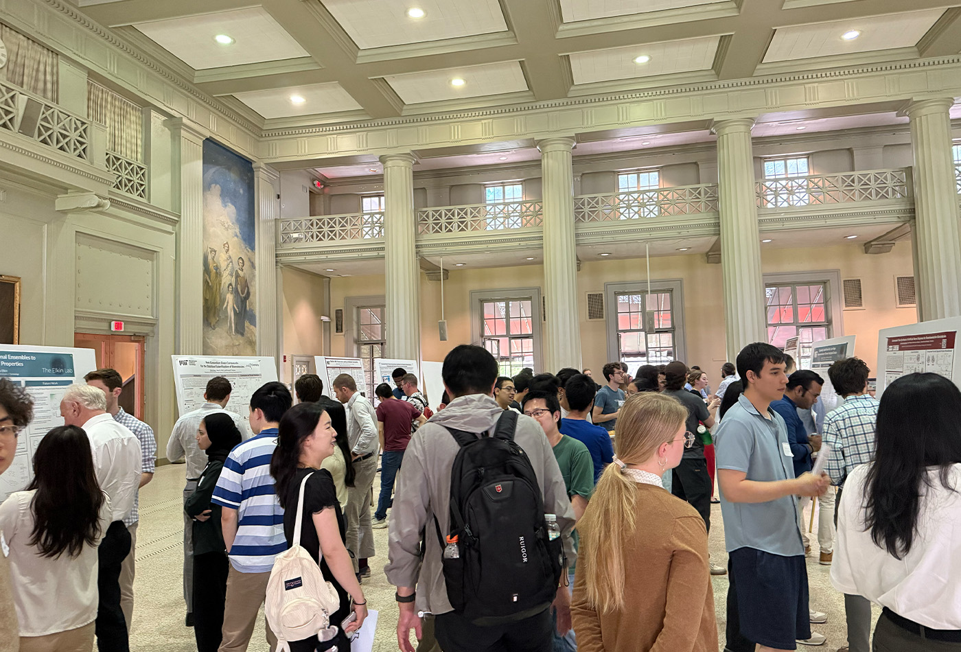 A group of attendees stand in the cavernous Morss Hall.
