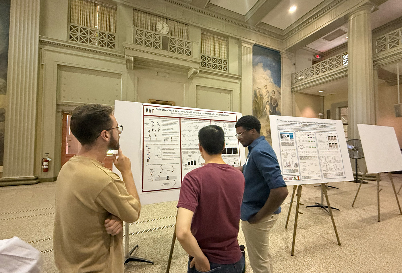 Gerard Porter stands in front of a poster and indicates toward it as others look on.
