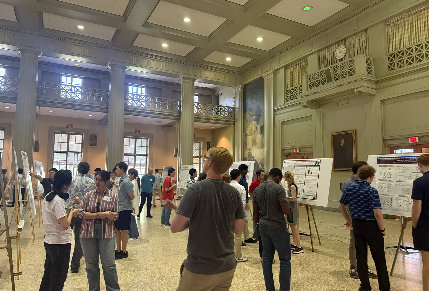 A group of attendees stand in the cavernous Morss Hall.