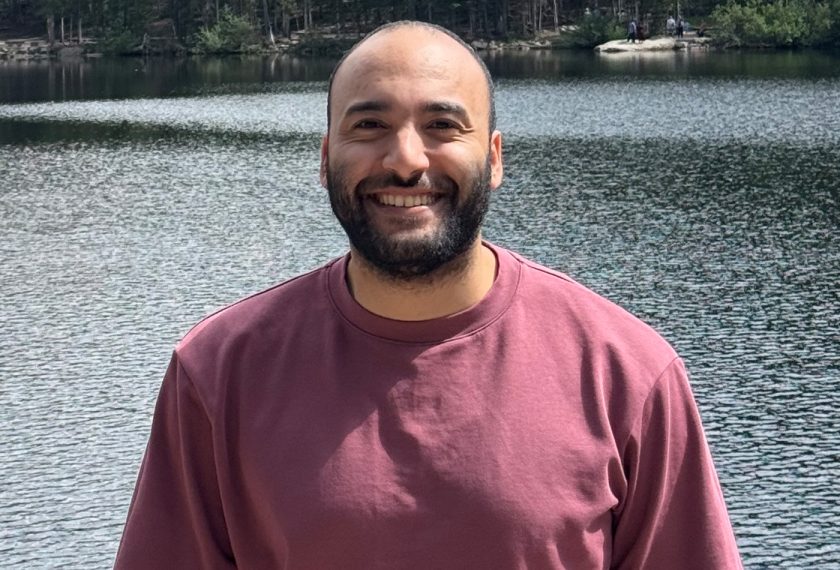 Deiaa Harraz smiles in front of a majestic body of water.