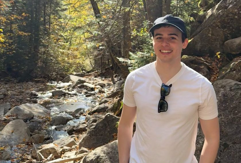 Seth Furniss smiles in the forest.