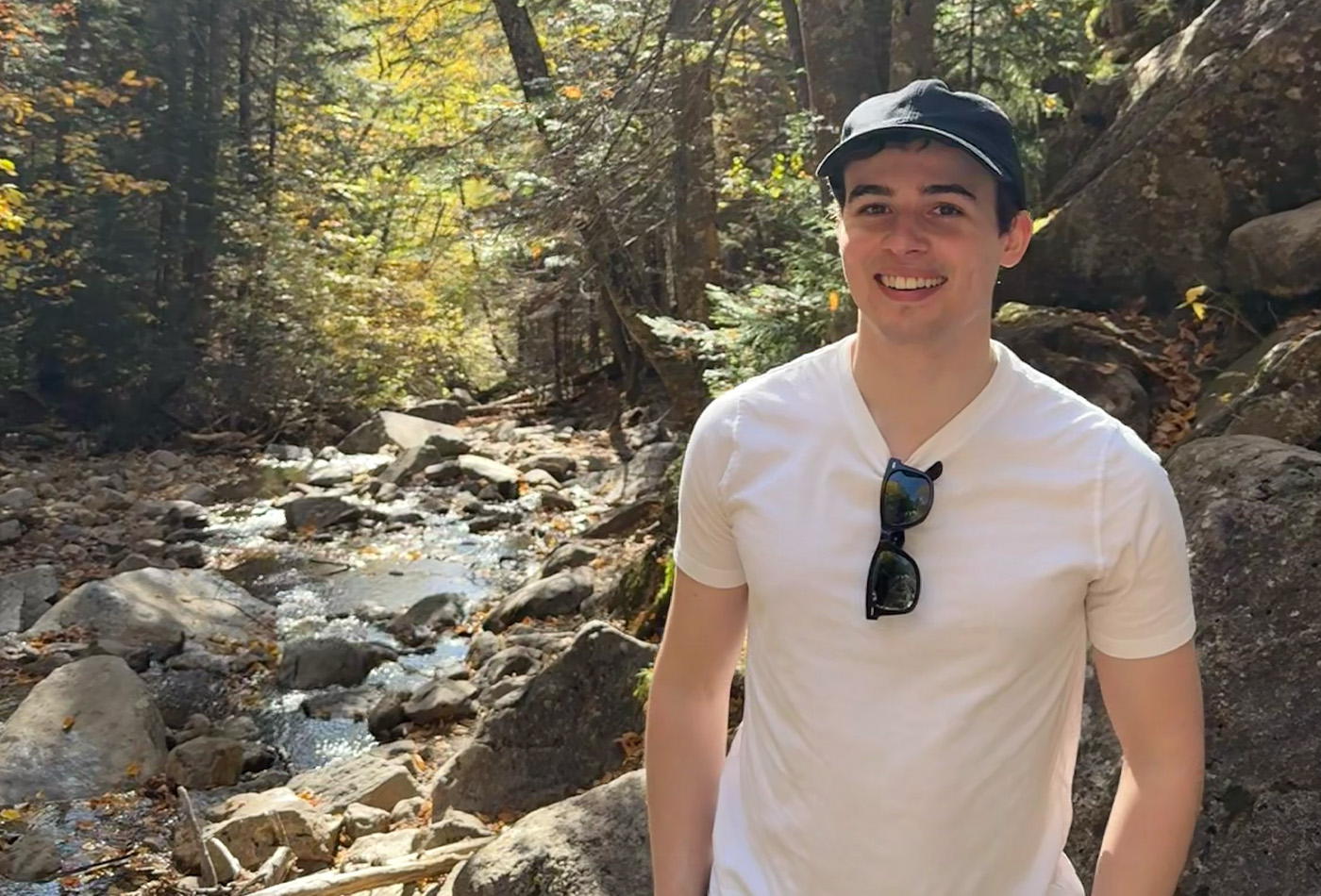 Seth Furniss smiles in the forest.