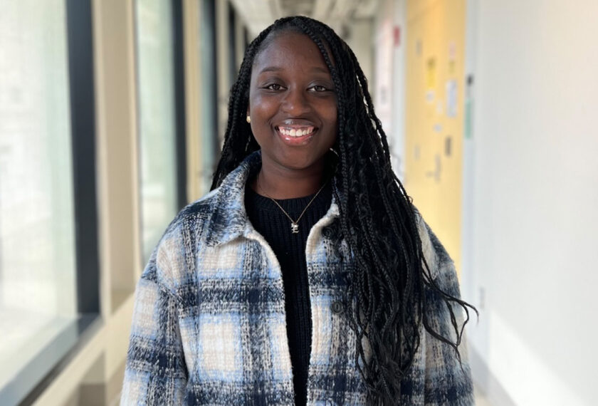 Ekua Beneman smiles in a hallway.