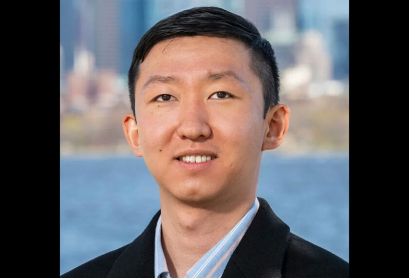Alvin Meng smiles in front of the Boston skyline.