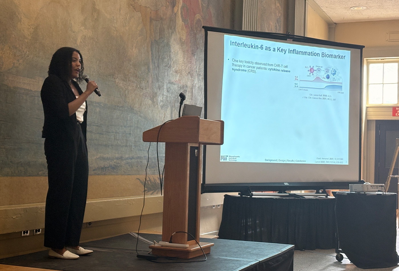 Jennifer Pierre-Louis stands in front of a power point presentation.