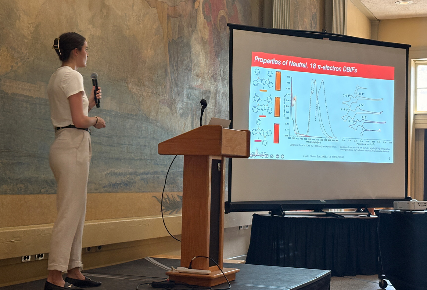 Colleen McAloon stands in front of a power point presentation.