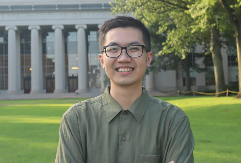 Minh Le smiles in front of a building at MIT.