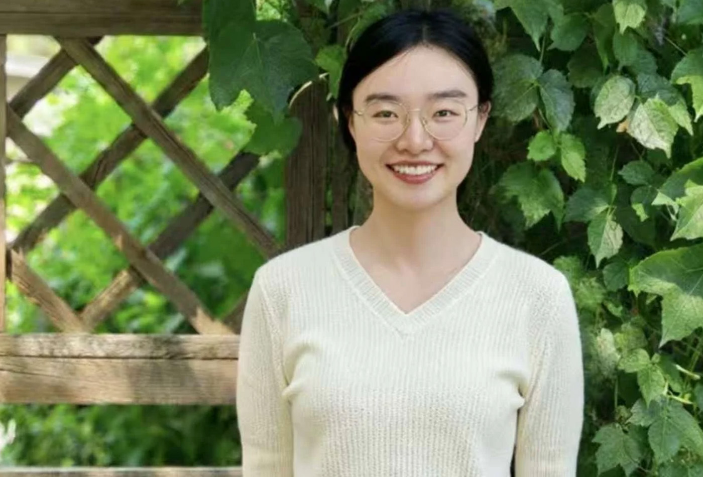 Mengyao Li smiles in front of an ivy-covered trellis.