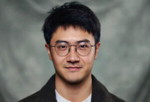 Wenlai Han smiles in front of a gray backdrop.