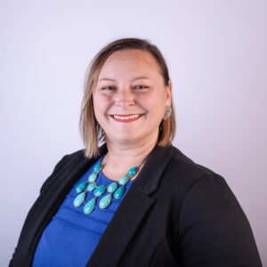 Karen Baird smiles in front of a blue background.