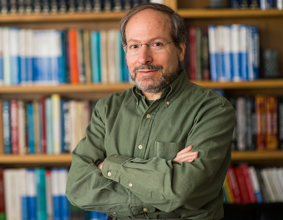 Headshot of Rick Danheiser standing in front of a shelf of books.