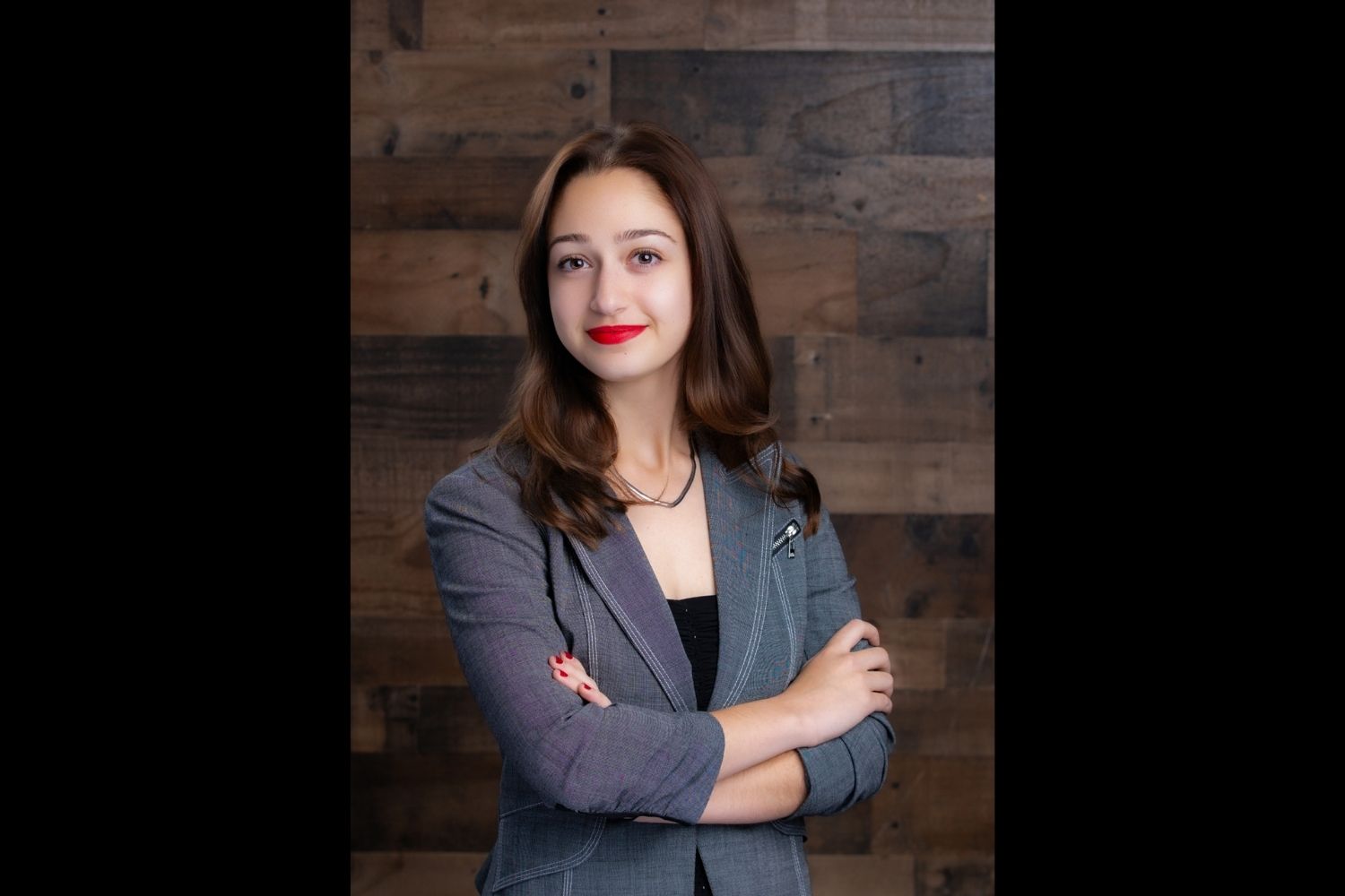 Georgia Voyiatzis stands with arms crossed in front of a wooden backdrop.